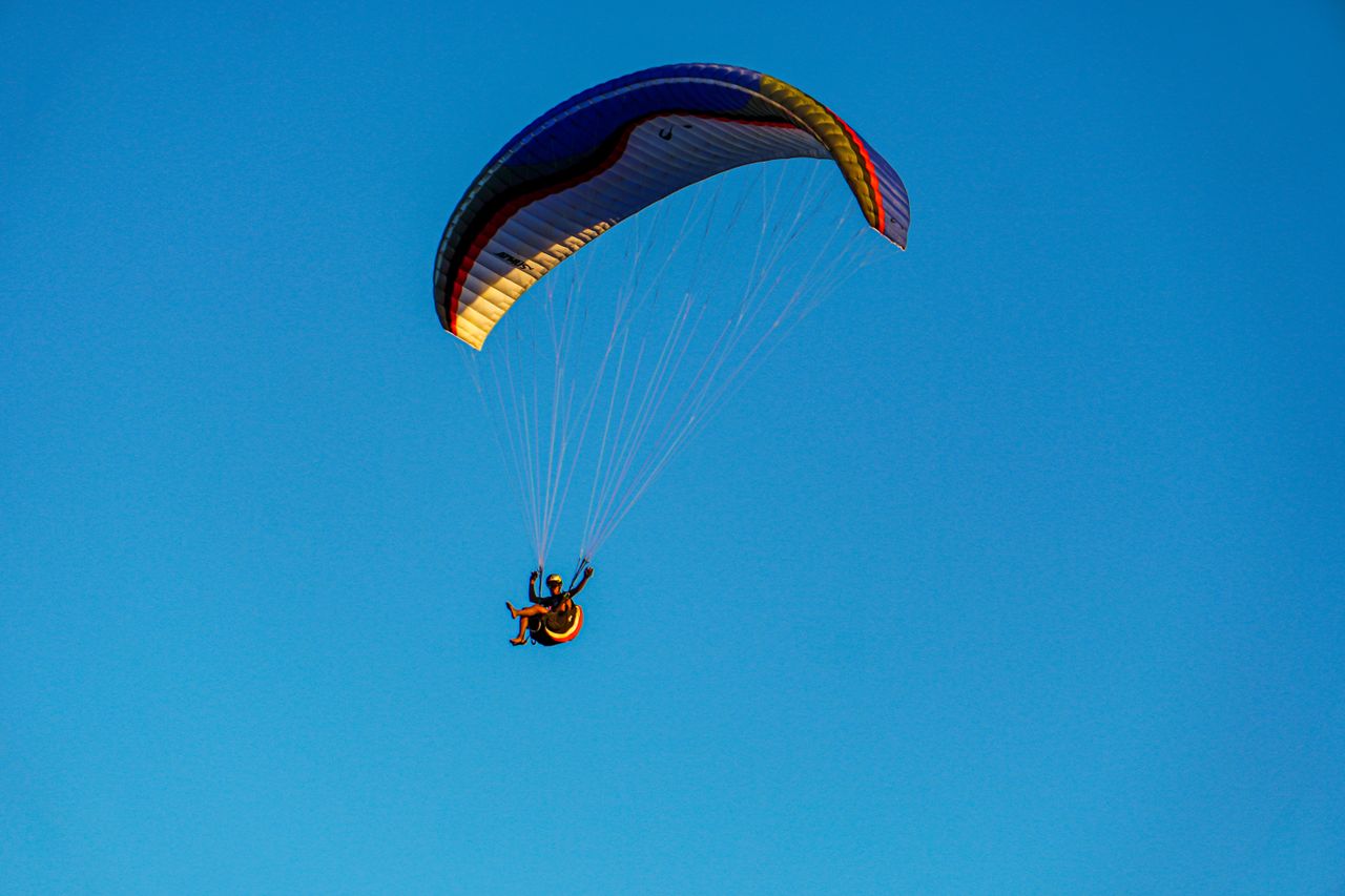 gallery-01 An exhilarating paragliding experience against a bright blue sky, capturing the thrill of flight and adventure.