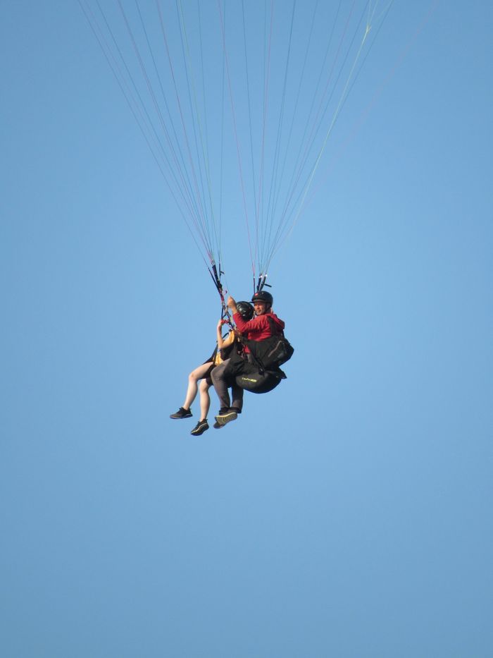 services-03 Enjoy the thrill of tandem paragliding against a clear blue sky, perfect for adventure seekers.